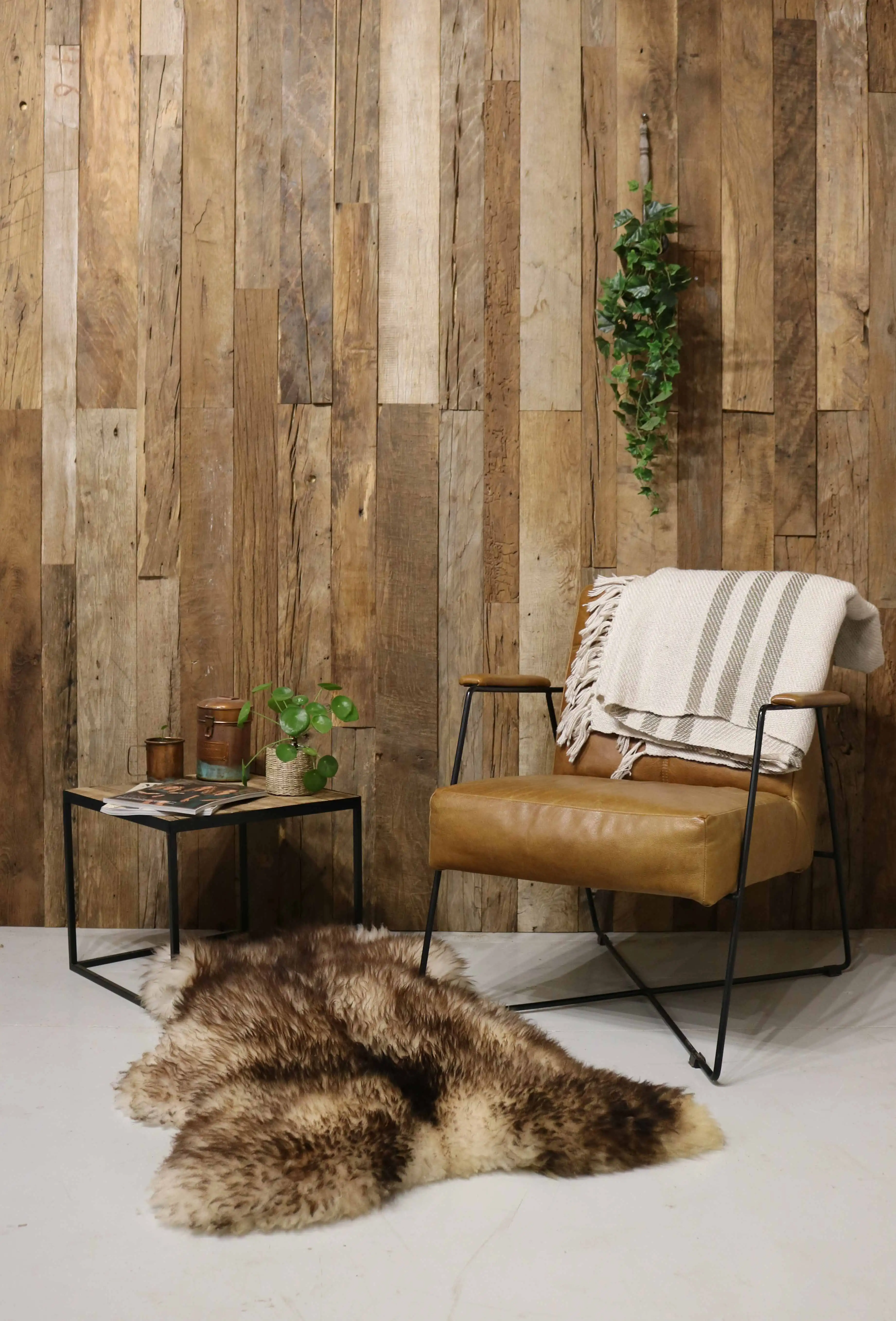 Altholz Wandverkleidung mit Sessel, Beistelltisch und Fellteppich.