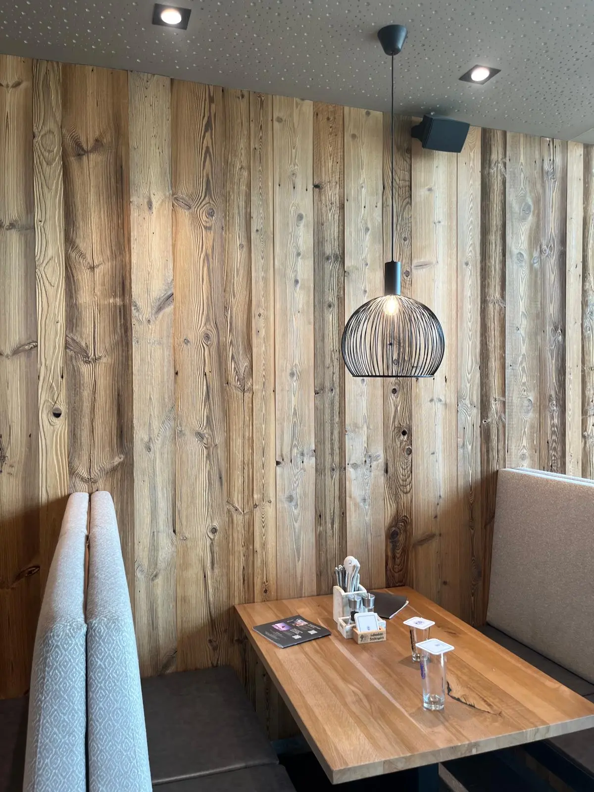 Altholz Wandverkleidung im Restaurant mit Holztisch und Sitzbank.