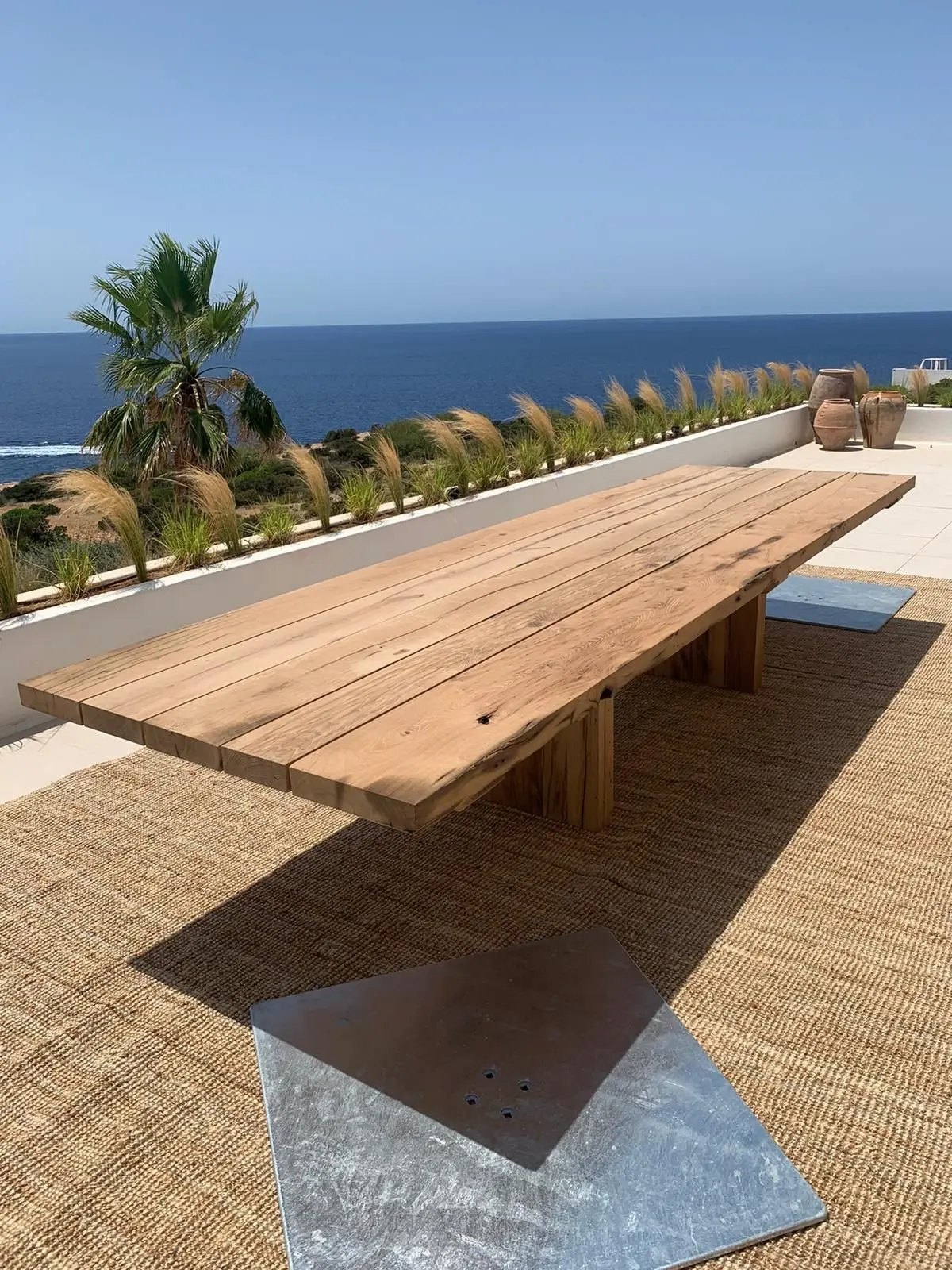 Langer Esstisch aus Altholz-Eiche auf einer sonnigen Terrasse mit Meerblick