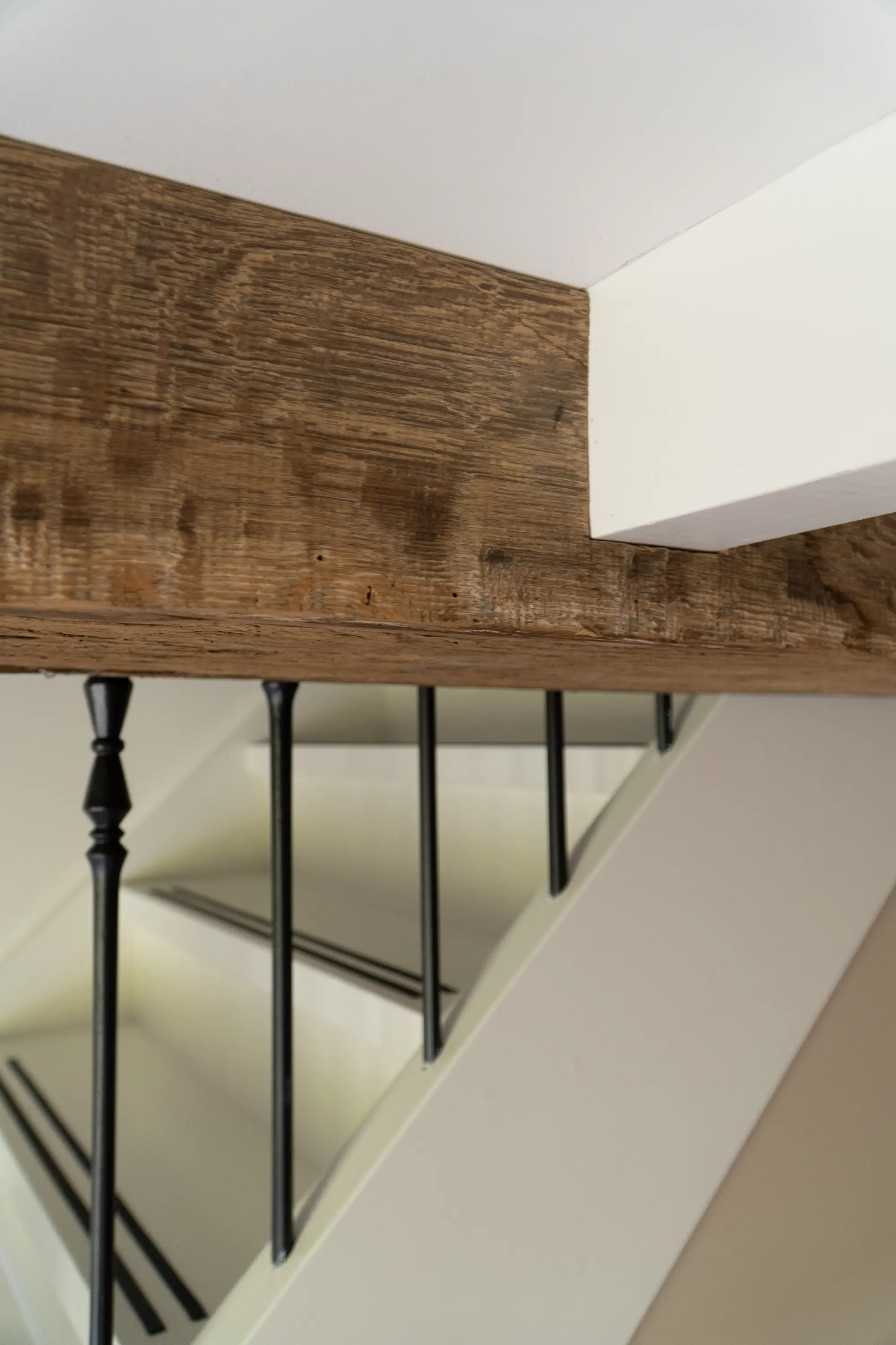 Charaktervolle Wandverkleidung aus Altholz neben einer Treppe mit schwarzem Metallgeländer
